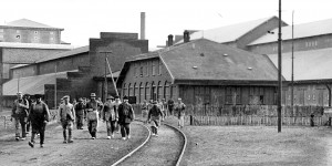 Archiwalny obrazek socjologiczny. Robotnicy wychodzący z fabryki po fajrancie. W środku historyczny budynek dyrekcji Zakładu. Z prawej magazyn superfostatu